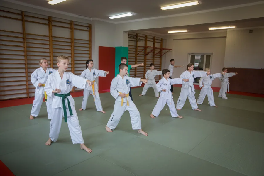 Dzieci w dobokach ćwiczą uderzenia na treningu Taekwon-do w Guk Gi